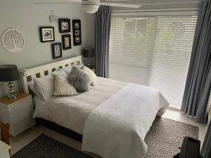 a bedroom with a white bed with pillows and a window at Paperbark Bed & Breakfast in Brisbane