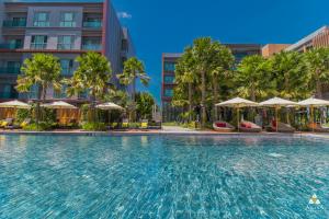 einen Pool in einem Hotel mit Palmen und Sonnenschirmen in der Unterkunft Aisana Hotel Korat in Nakhon Ratchasima