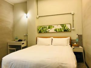 een slaapkamer met een groot wit bed met 2 kussens bij Chia Kon Hotel in Chiayi City