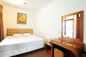 Schlafzimmer mit einem Bett, einem Schreibtisch und einem Spiegel in der Unterkunft De'Qur Hotel Bandung in Bandung