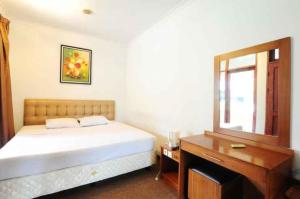 a bedroom with a bed and a desk and a mirror at De'Qur Hotel Bandung in Bandung