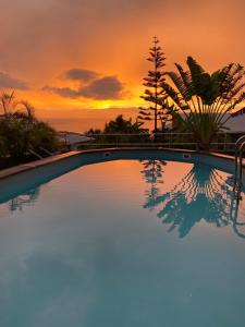 une piscine avec vue sur le coucher du soleil en arrière-plan dans l'établissement Villa Moai 974, à Saint-Leu