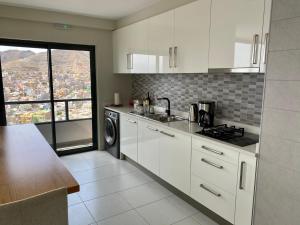 a kitchen with white cabinets and a view of a city at Ocean View Stay in Mindelo