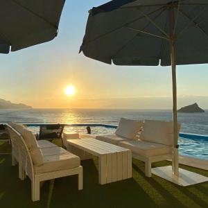 um pátio com uma mesa, cadeiras e um guarda-sol em Ocean View Stay em Mindelo