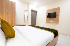 um quarto com uma cama branca e uma televisão na parede em Hotel Prime Inn em Warangal