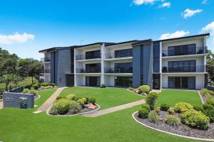 an apartment building with a lawn in front of it at Illawong Apartments in Mooloolaba