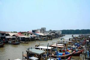 um grupo de barcos ancorados num rio com casas em Ks Homestay em Taiping