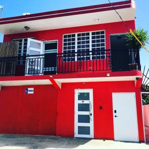 
a red and white building with a red door at Casita Paraiso in Aguadilla
