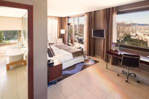 a hotel room with a bed and a desk and a window at Hotel Miramar Barcelona GL in Barcelona