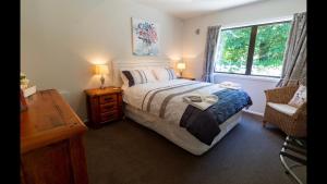 a bedroom with a bed and a window and a chair at Bellbird Guest Accommodation in Akaroa