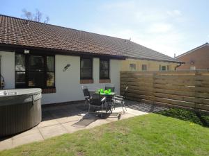 a patio with a table and chairs and a fence at Appin Lodge in Aviemore
