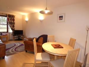 a living room with a table and chairs and a television at Appin Lodge in Aviemore