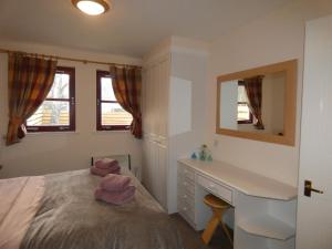 a bedroom with a bed and a desk and a mirror at Appin Lodge in Aviemore