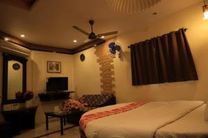 a bedroom with a bed and a living room at Hotel Pratap Heritage in Mahabaleshwar