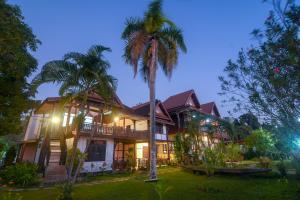 une maison avec un palmier en face dans l'établissement Kongmany Colonial House, à Muang Không