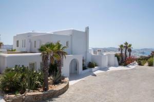 a white house with palm trees in front of it at Diles Villas & Suites Mykonos in Tourlos