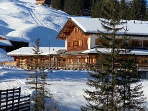 ein großes Holzhaus mit Schnee auf dem Boden in der Unterkunft Erezsässhütte in Klosters