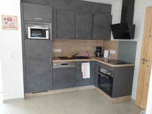 eine Küche mit grauen Schränken und einer Spüle in der Unterkunft Les balcons la haie des grisselles in Gérardmer + 1 Foto