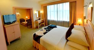ein Hotelzimmer mit einem großen Bett und einem TV in der Unterkunft Emerald Puteri Hotel in Sungai Petani