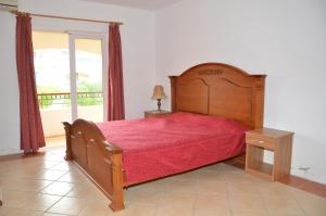 een slaapkamer met een houten bed met een rode sprei bij Residences Beach Apartment in Flic-en-Flac
