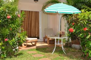 a patio with a table and an umbrella at Residences Beach Apartment in Flic-en-Flac