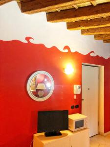 a room with a red wall with a tv and a mirror at Terrazza Tassis Charme&Relax in Bergamo
