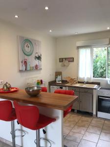 uma cozinha com uma mesa de madeira e cadeiras vermelhas em Appartement PALAZZI 2 em L'Île-Rousse