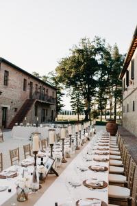 un lungo tavolo con piatti bianchi e candele sopra di Agriturismo San Galgano a Chiusdino