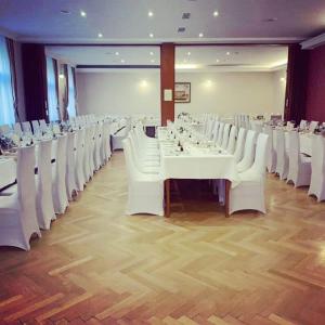 un salón de banquetes con mesas blancas y sillas blancas en Hotel Zvezda, en Murska Sobota