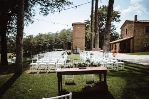 un matrimonio all'aperto con sedie bianche e un tavolo con fiori di Agriturismo San Galgano a Chiusdino