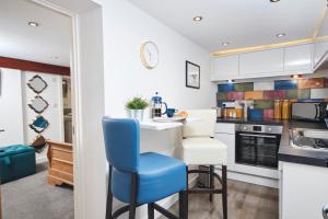 eine Küche mit weißen Schränken und blauen Stühlen in der Unterkunft The Little Apartment in Kegworth