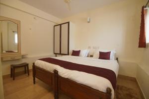 1 dormitorio con 1 cama grande y espejo en Cliffhanger Retreat, en Yercaud