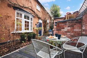 a patio with a table and chairs and a brick building at The Little Apartment in Kegworth