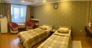 ペルミにあるHotel Khozyayushkaのベッドルーム1室(ベッド2台、壁掛け時計付)