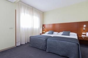 a bedroom with two beds and a large window at Porcel Torre Garden in Madrid