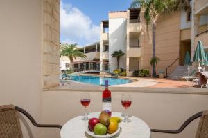 a table with two glasses of wine and a bowl of fruit at Creta Palm Resort Hotel & Apartments in Stalos