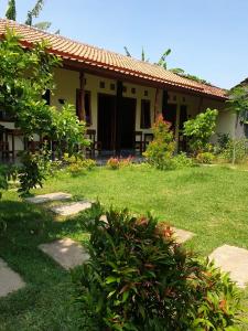 een huis met een groene tuin met een grasveld bij Sunrise Banyuwangi Homestay in Banyuwangi