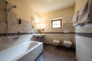 a bathroom with two toilets and a tub and a sink at Hotel Seerast in Ultimo