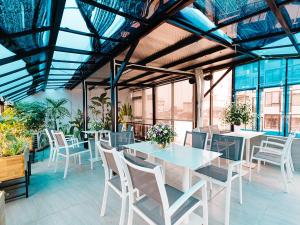 a dining room with tables and chairs and plants at Ha Noi Re Hostel in Hanoi