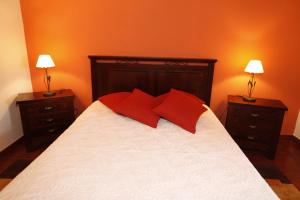 a bedroom with a bed with red pillows and two lamps at Casa capelinhos in Capelo