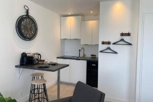 cocina con encimera y reloj en la pared en Le petit loft - Studio - WIFI - Coeur de ville - Parking en Pont-lʼAbbé