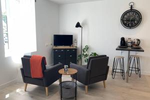 sala de estar con 2 sillas, mesa y reloj en Le petit loft - Studio - WIFI - Coeur de ville - Parking en Pont-lʼAbbé