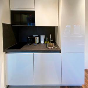 een kleine keuken met witte kasten en een magnetron bij Nurban Apartments Oldtown in Neurenberg