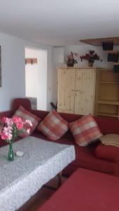 ein Wohnzimmer mit einer roten Couch mit Kissen in der Unterkunft Ferienwohnungen Langer in Kurort Altenberg