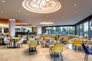 un restaurant avec des tables et des chaises et un grand lustre dans l'établissement Club Marmara Rhodes Doreta Beach, à Theologos