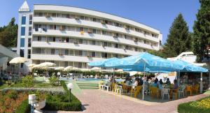 people sitting under umbrellas in front of a building at Hotel Oasis in Albena
