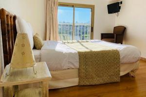 a bedroom with a bed with a window and a table at Avocado Hôtel in Saint-Jeannet