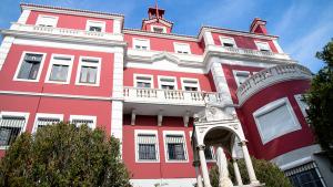 een rood-wit gebouw met een boog ervoor bij Sant Jordi Hostels Lisbon in Lissabon