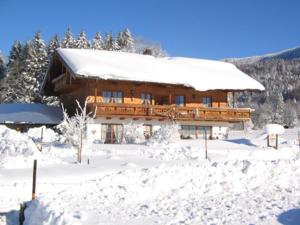 un grand bâtiment en bois recouvert de neige dans l'établissement Haus Jung - Chiemgau Karte, à Inzell