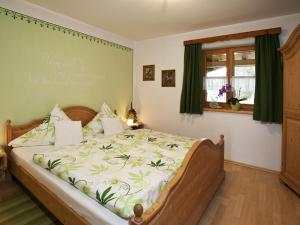 a bedroom with a large bed with a green comforter at Haus Jung - Chiemgau Karte in Inzell +2 photos